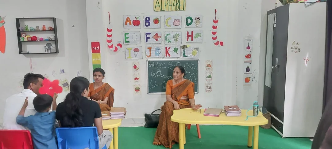 A classroom wall of hand-made alphabet charts above low tables and chairs