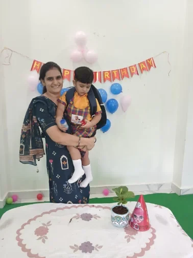 A member of the Wonder Bees team holding a child at a classroom birthday celebration