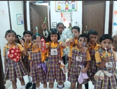 Young children in Wonder Bees uniform holding craft items they have made, standing together in the classroom doorway